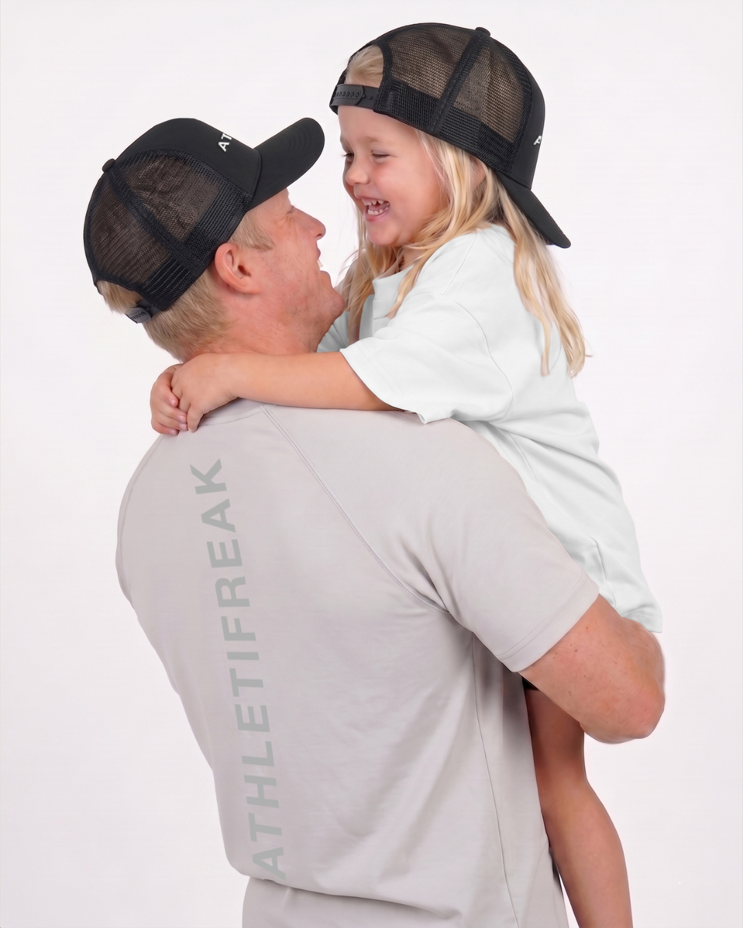 Man holding a child both wearing black caps with a white background